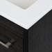 Closeup of corner of white cultured marble sink top on Lir 24.5" W dark woodgrain cabinet-style bathroom vanity 