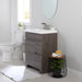 Muriel 24.5" W dark woodgrain cabinet-style 1-door, 2-drawer bathroom vanity installed in bathroom with toilet and plant