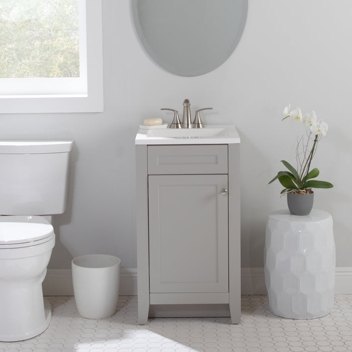 Wyre 18.25" W gray shaker-style 1-door bathroom vanity with satin nickel pull, white sink top installed in bathroom with plant and toilet